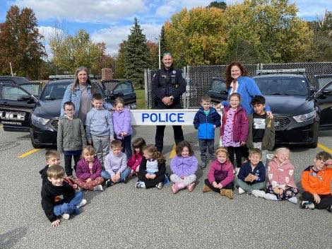 A police officer poses for a photo with a group of students.